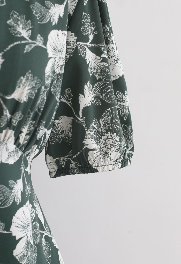Robe portefeuille vert foncé fleurie nouée à la taille