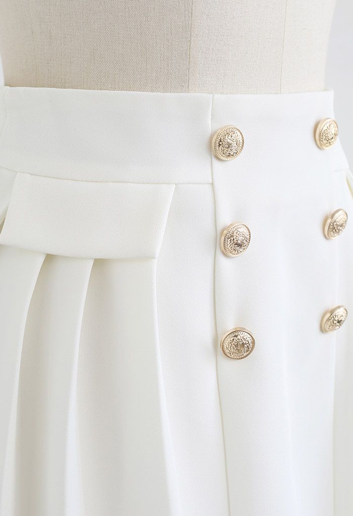Mini-jupe plissée à boutons dorés subtils en blanc