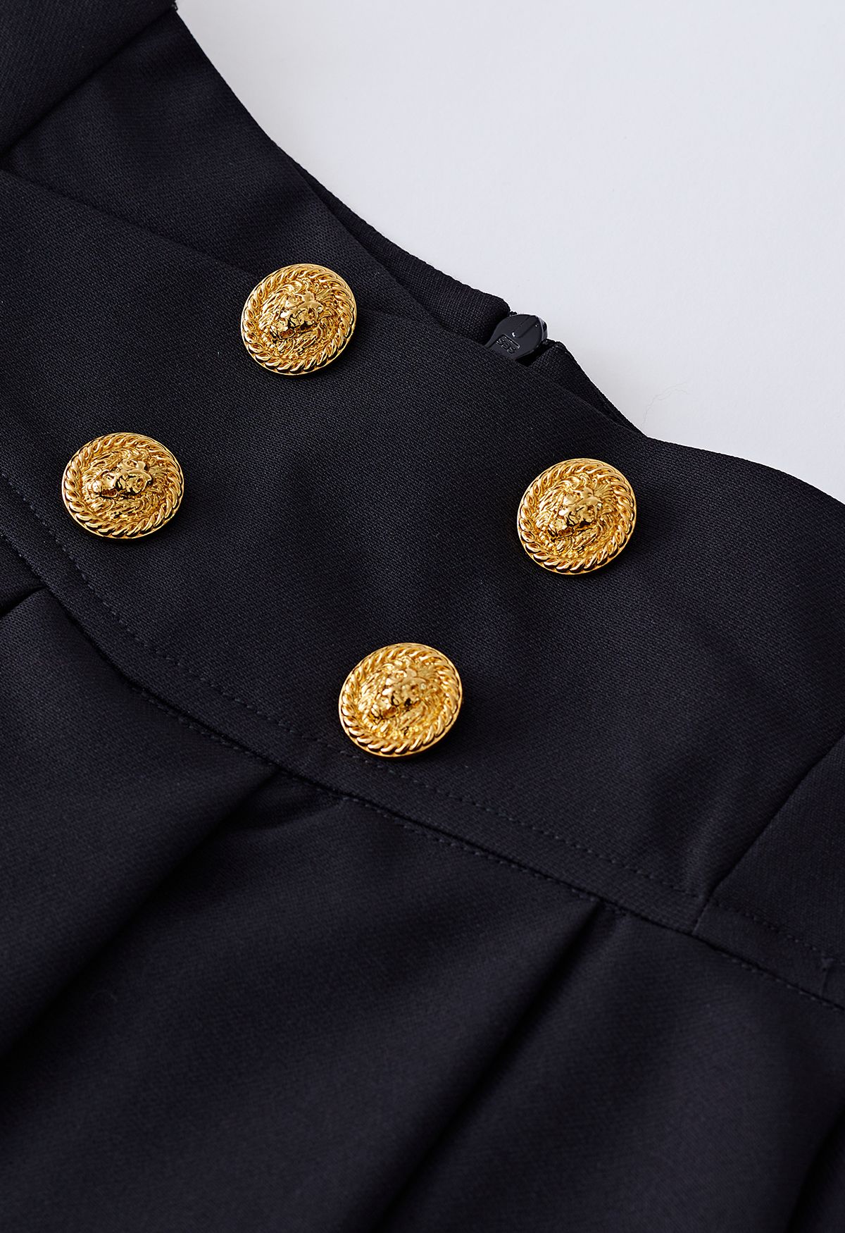 Mini-jupe évasée plissée à boutons dorés en noir