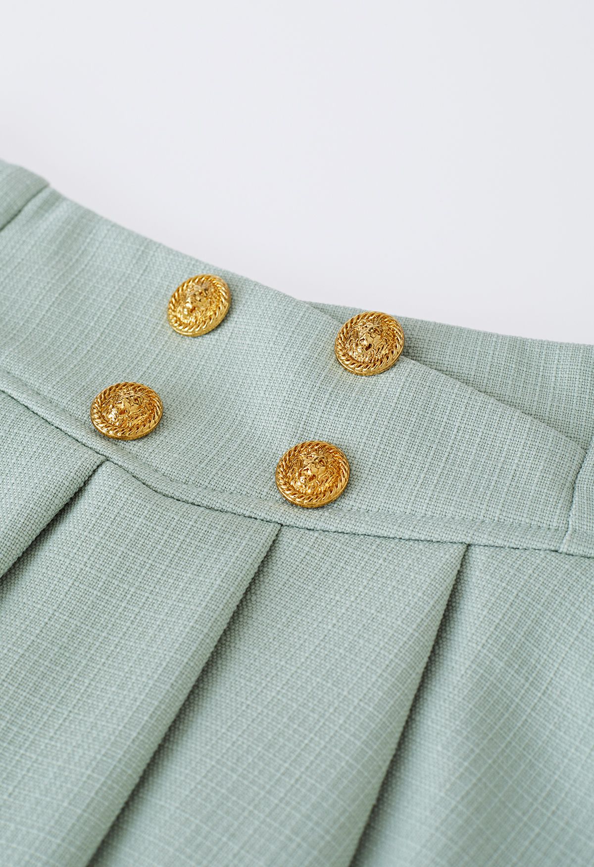 Mini-jupe évasée plissée à boutons dorés en pistache