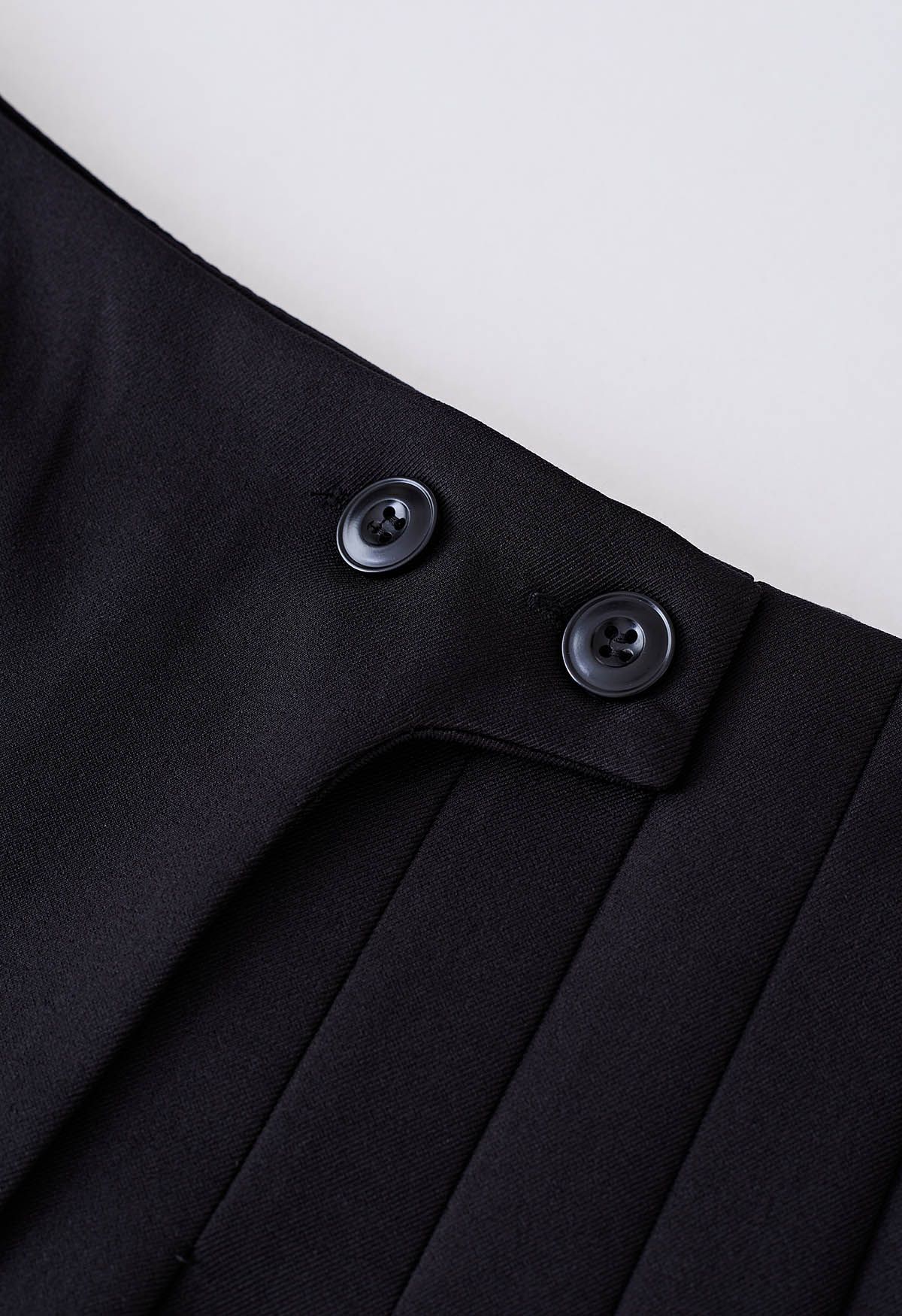 Mini-jupe plissée à deux boutons en noir