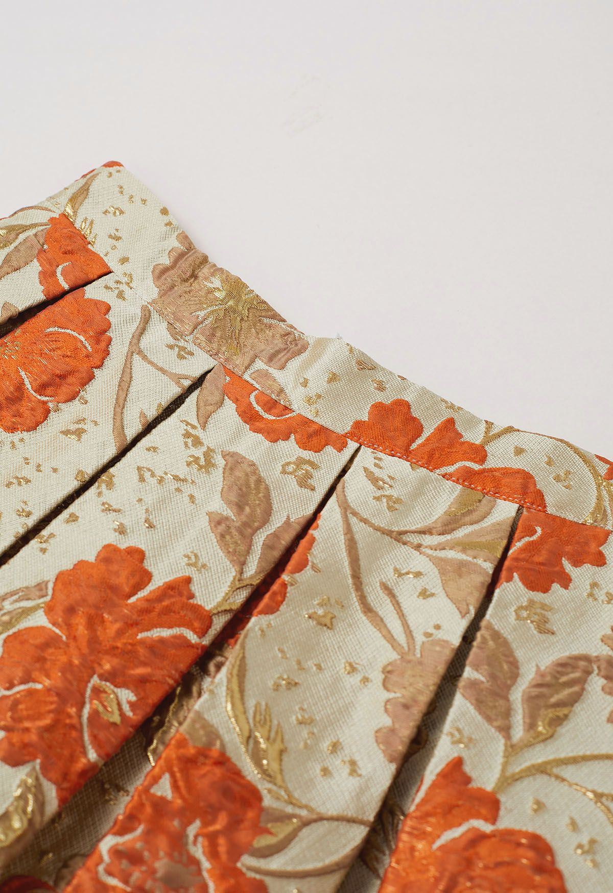 Jupe mi-longue plissée évasée en jacquard fleuri orné de motifs orange