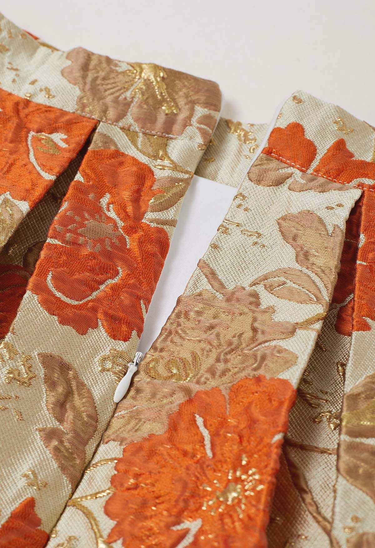 Jupe mi-longue plissée évasée en jacquard fleuri orné de motifs orange