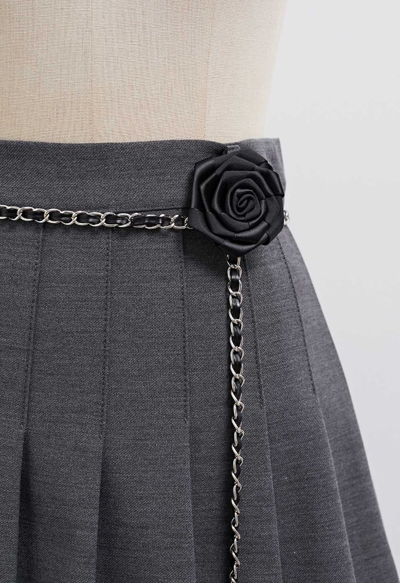 Mini-jupe plissée avec ceinture en chaîne et broche rose en couleur fumée