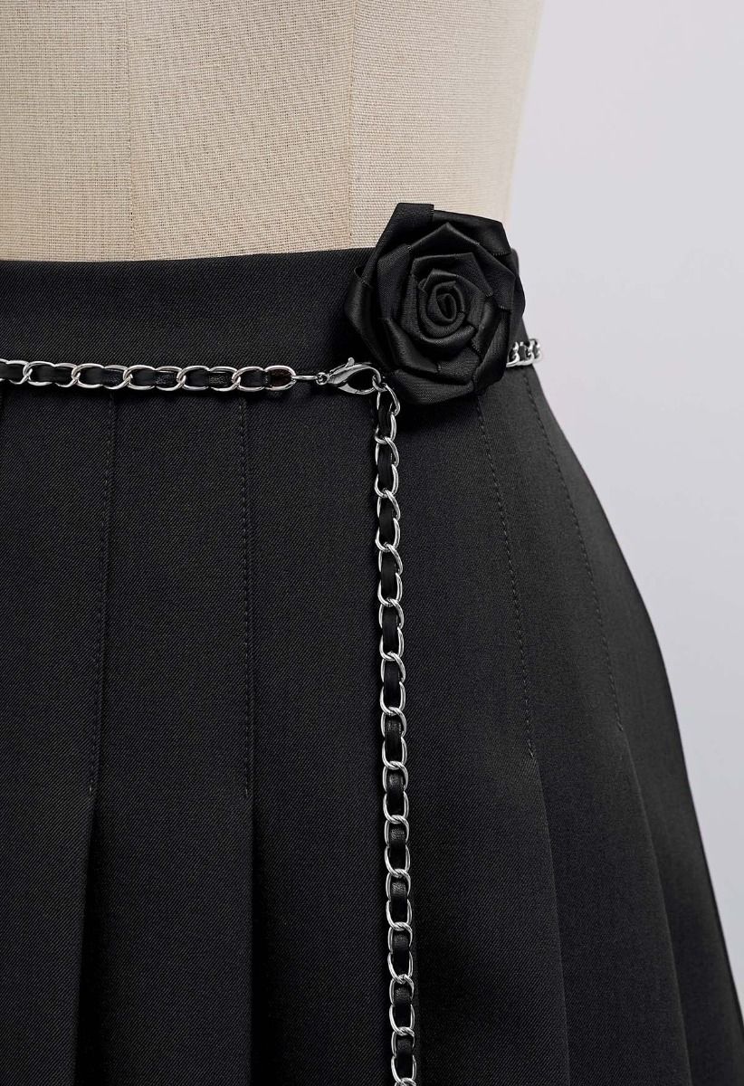 Mini-jupe plissée avec ceinture en chaîne et broche rose en noir