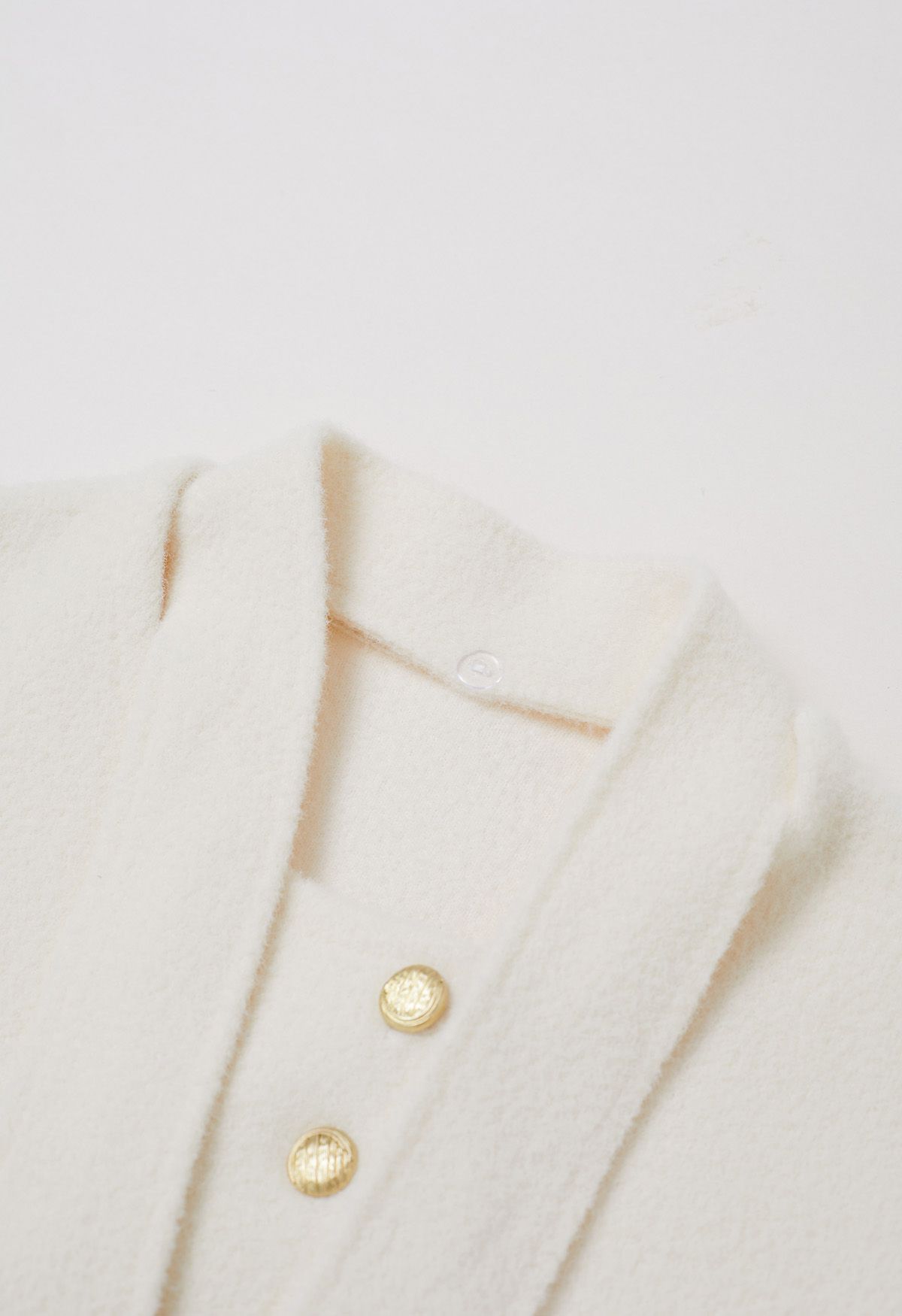 Manteau en tricot à boutons dorés amovibles avec col noué en crème