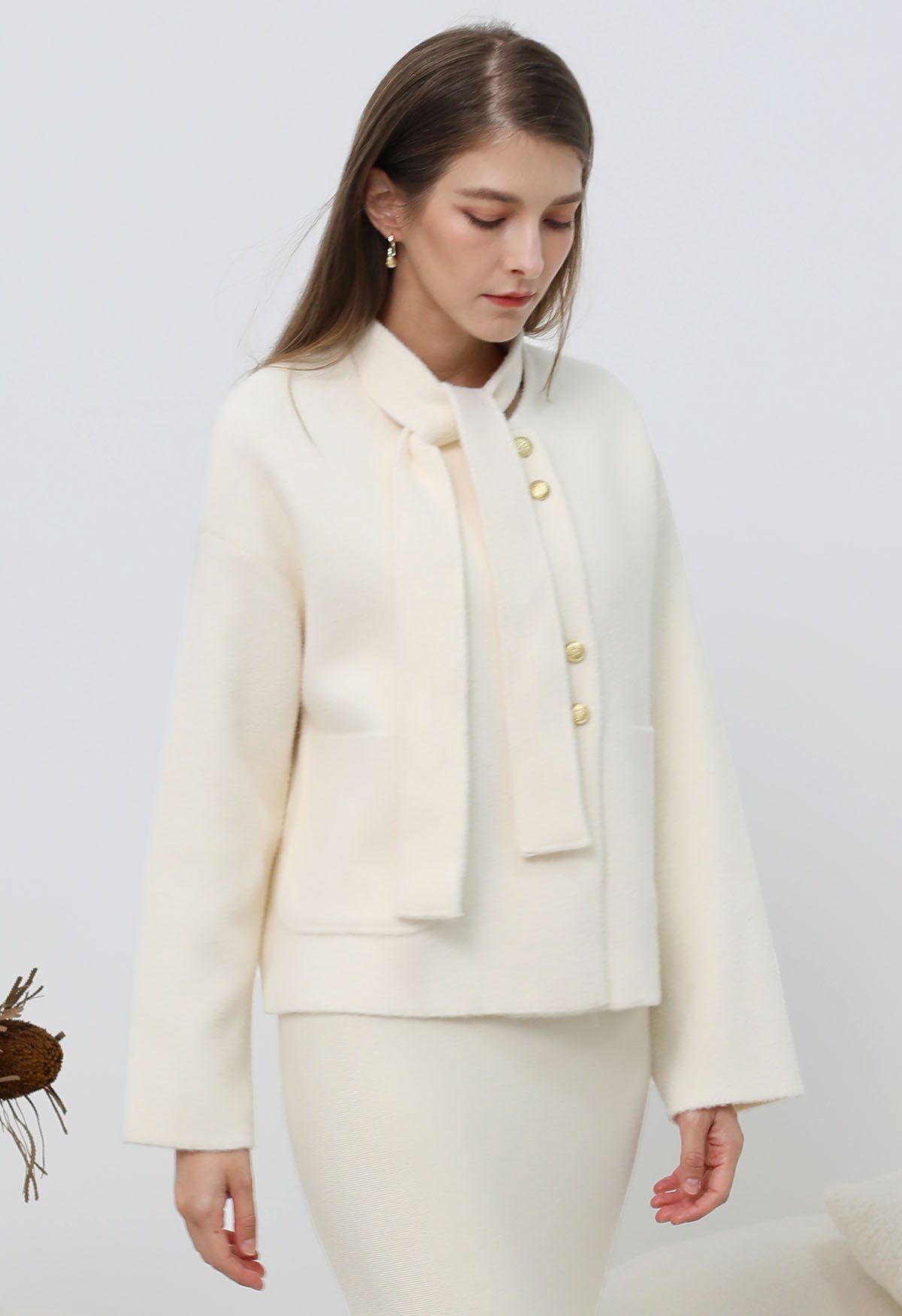 Manteau en tricot à boutons dorés amovibles avec col noué en crème