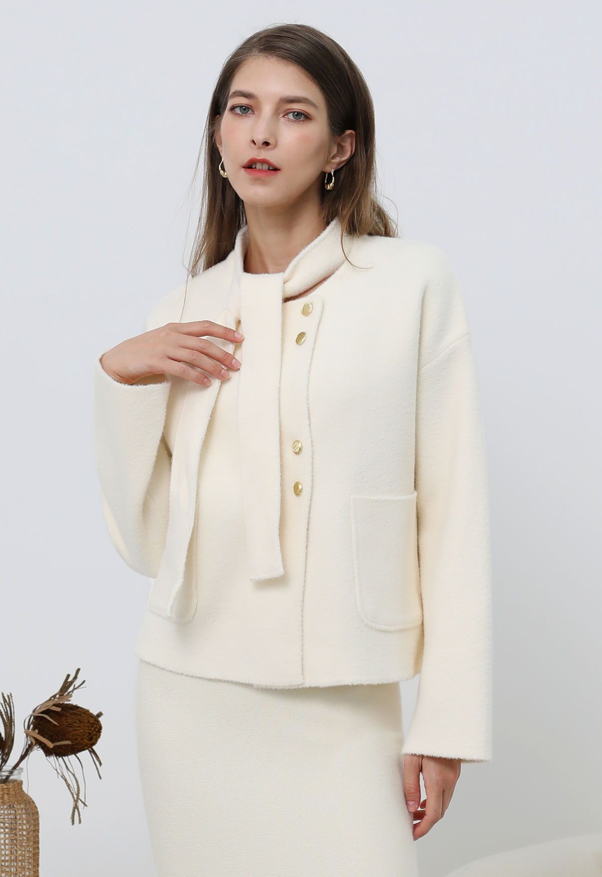 Manteau en tricot à boutons dorés amovibles avec col noué en crème