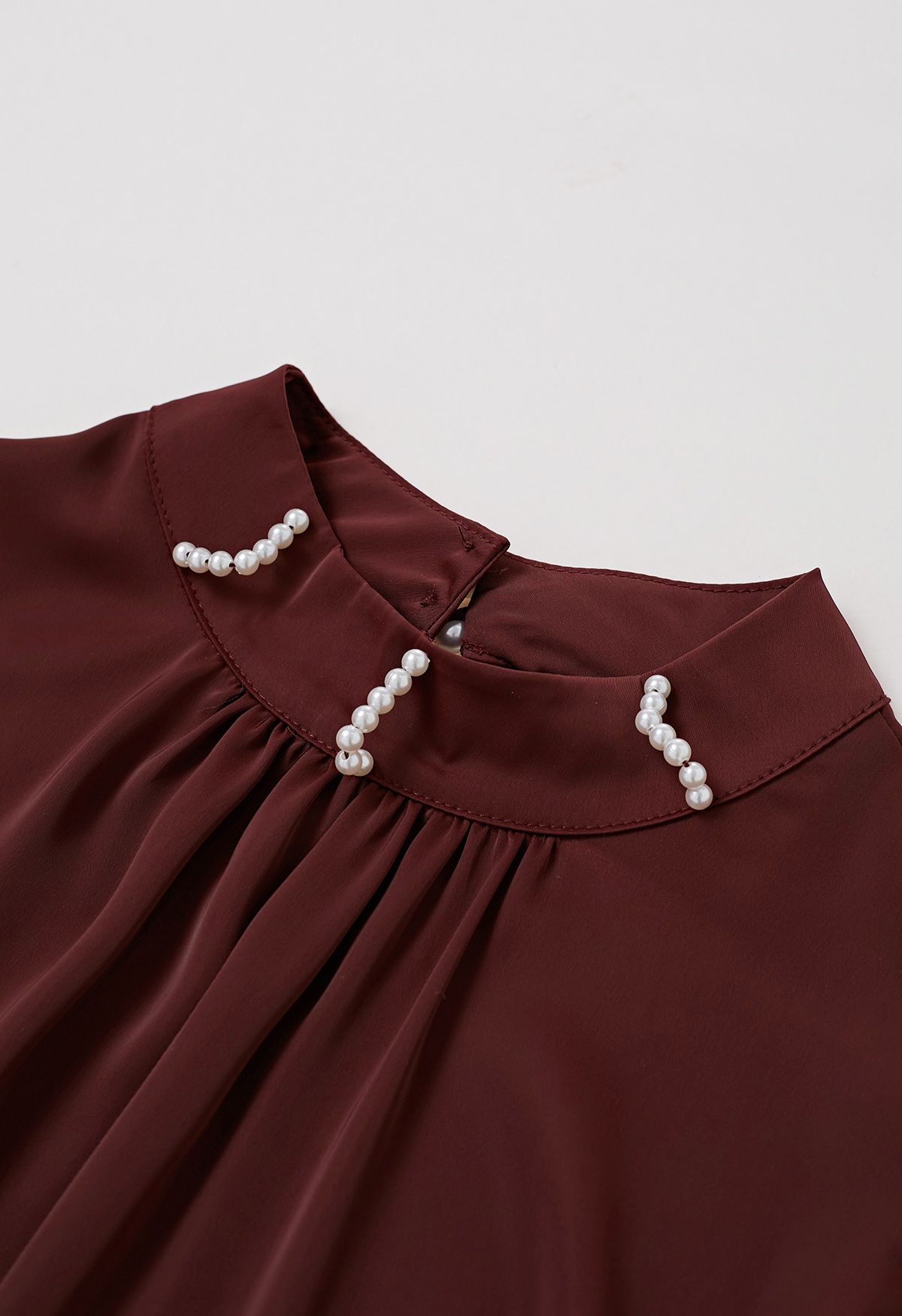 Haut en satin bordeaux avec nœud sur le côté et décolleté en perles