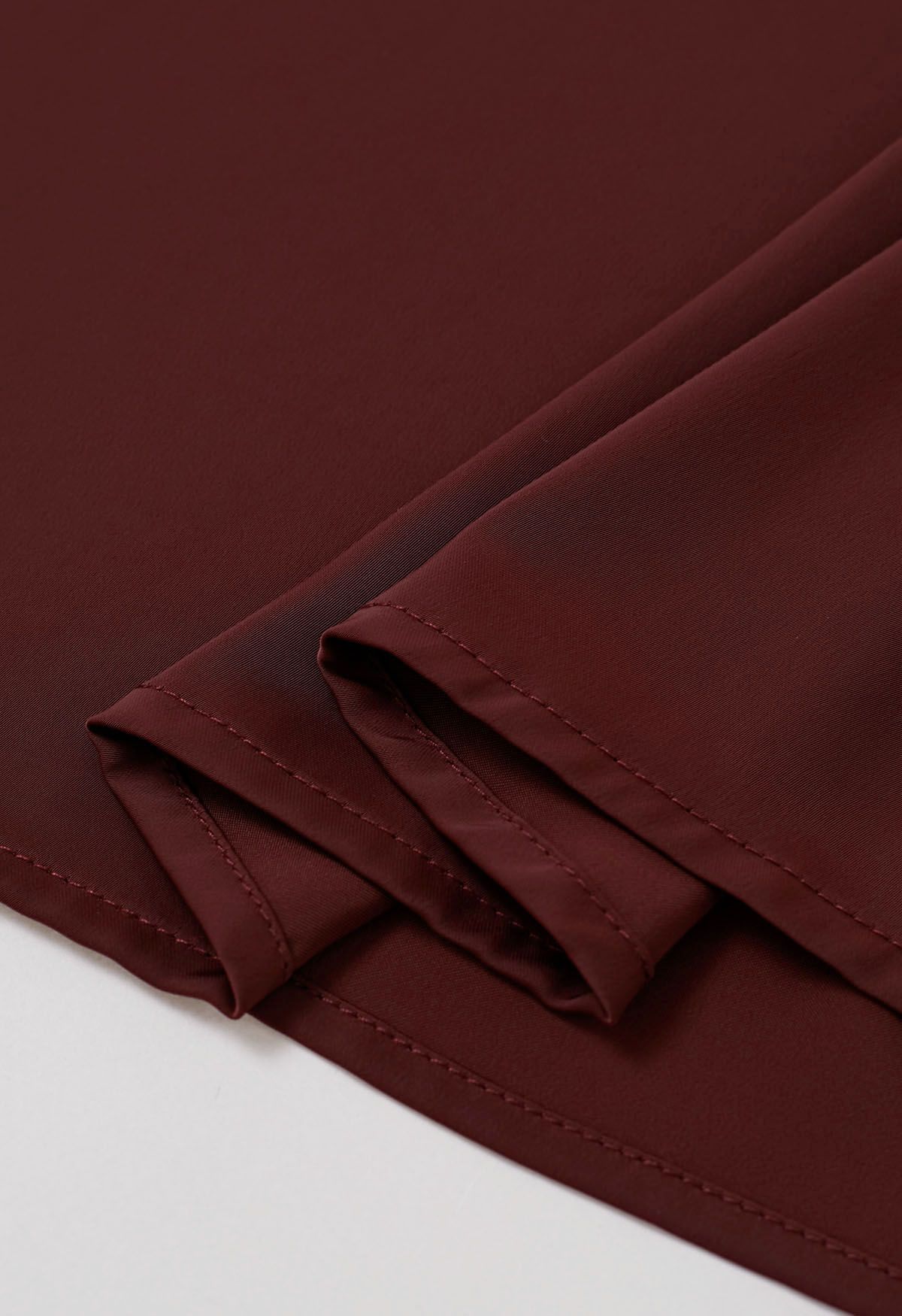 Haut en satin bordeaux avec nœud sur le côté et décolleté en perles