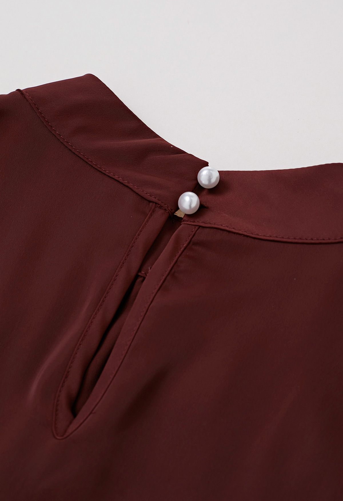 Haut en satin bordeaux avec nœud sur le côté et décolleté en perles