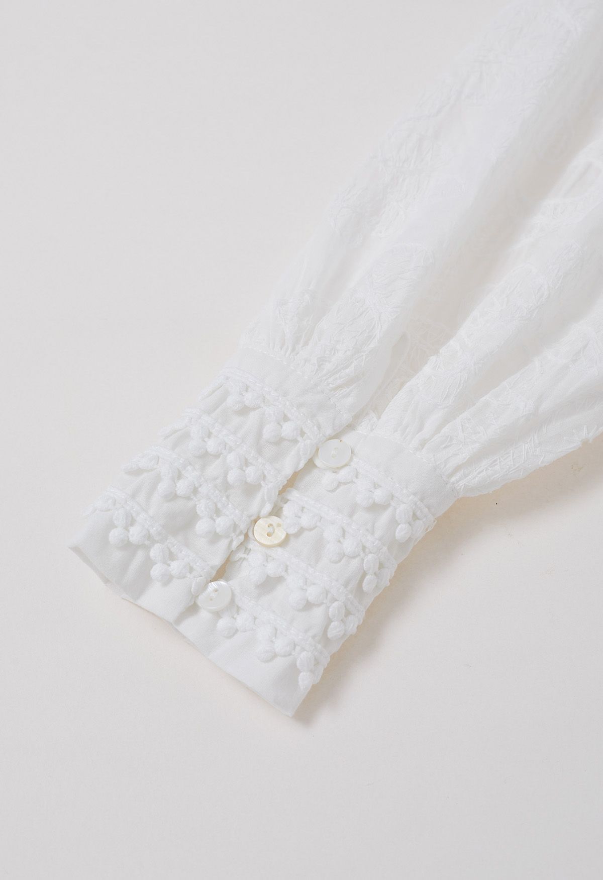 Robe longue boutonnée à pompons et broderies florales en blanc