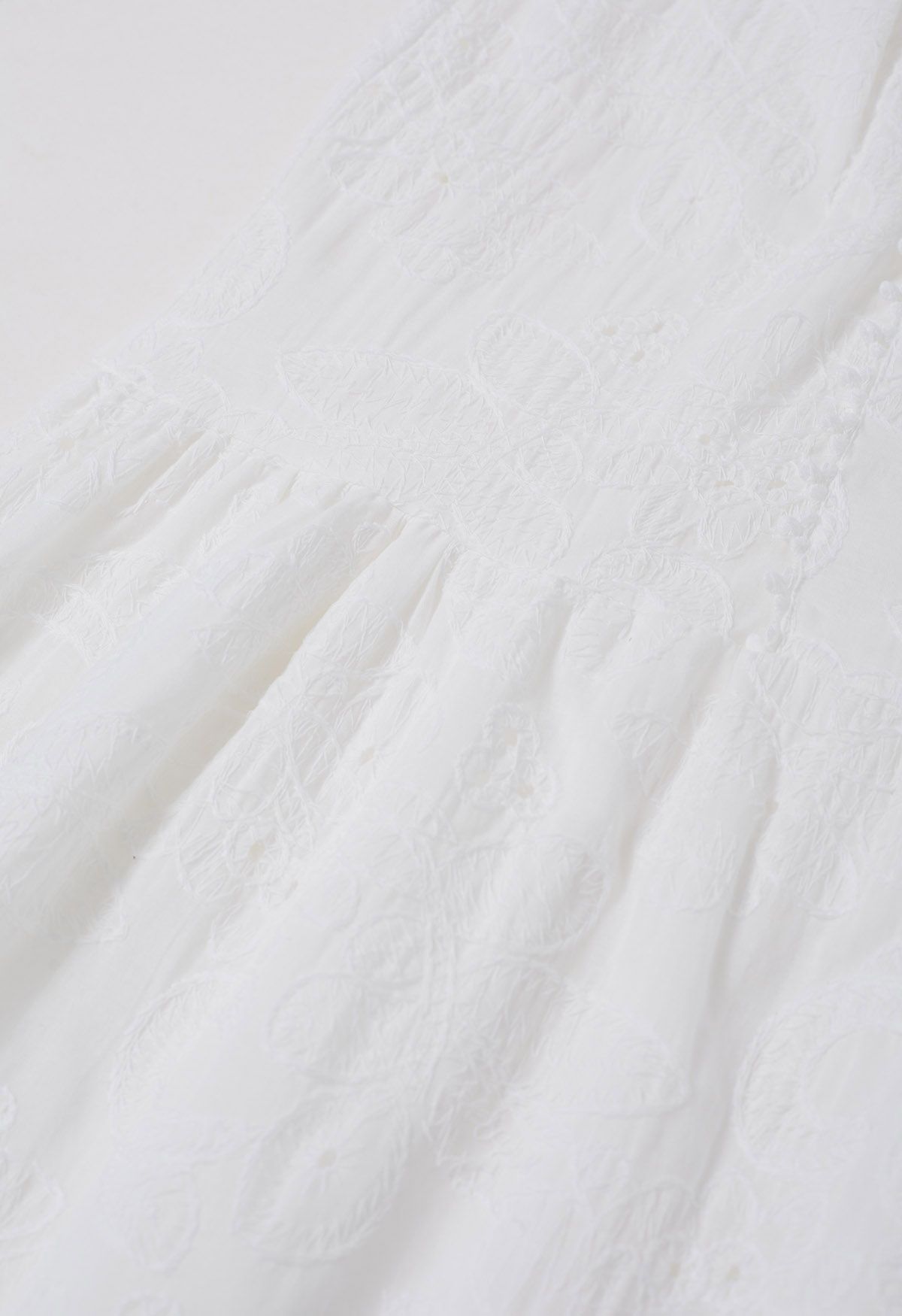 Robe longue boutonnée à pompons et broderies florales en blanc