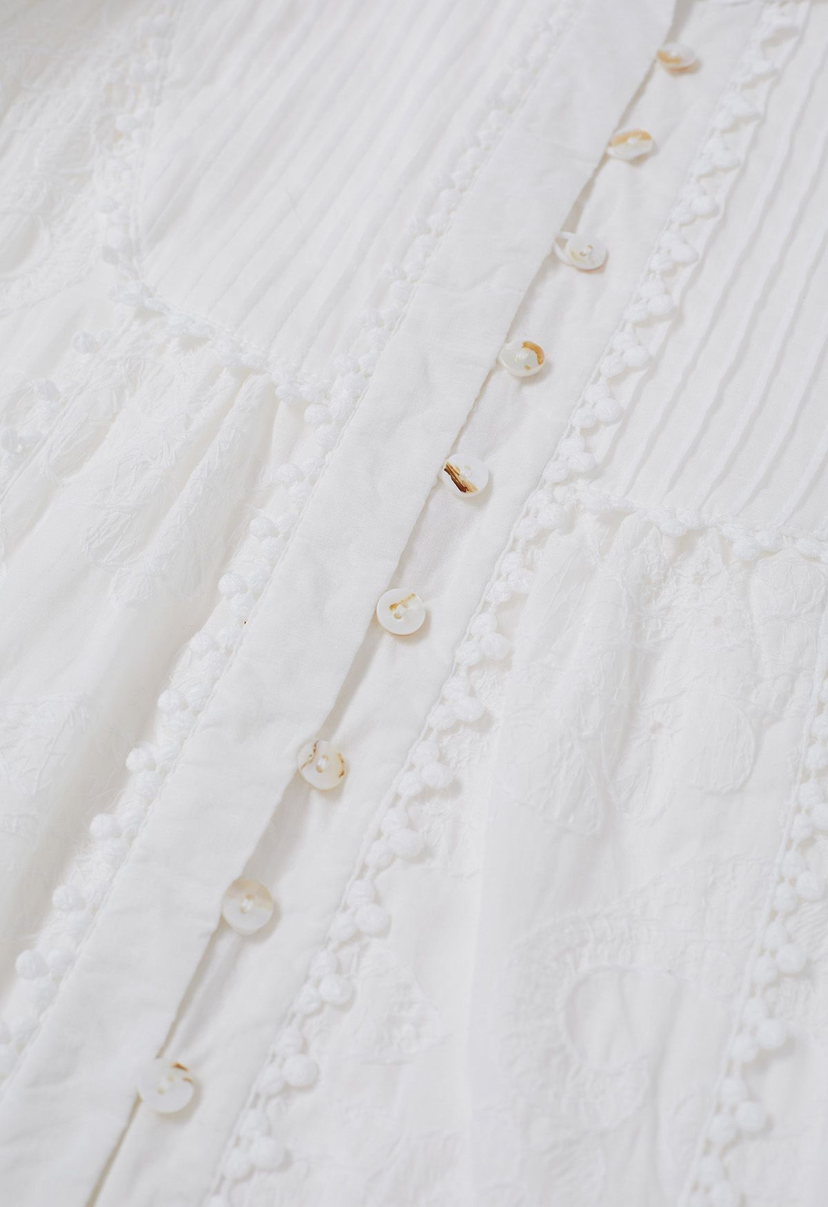 Robe longue boutonnée à pompons et broderies florales en blanc