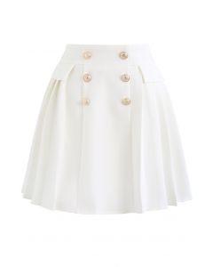 Mini-jupe plissée à boutons dorés subtils en blanc