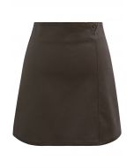 Mini-jupe en similicuir bordée de boutons en marron